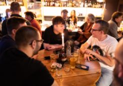 Drupal Mountain Camp 2025 - Splash Awards Party. Foto von Patrick Itten - patrickitten.ch / @patrickitten Leute sitzen in einer Bar um einen runden Tisch.